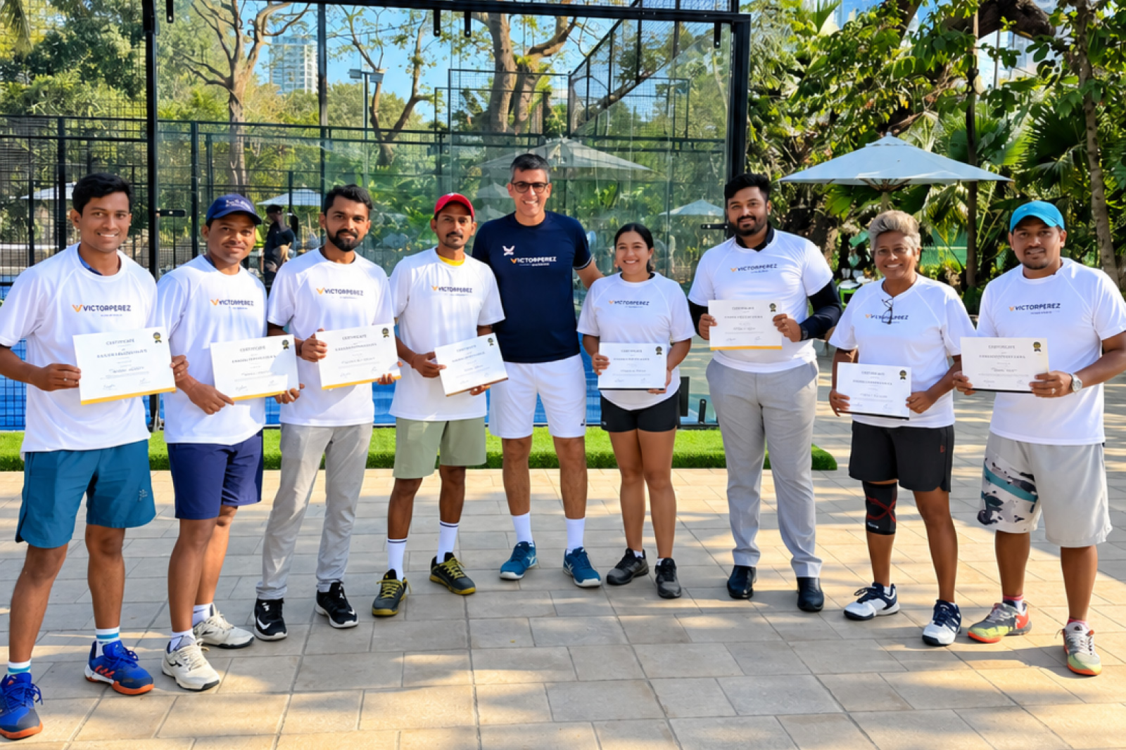 Victor Perez with eight newly certified padel coaches in India, each holding their Victor Perez Padel certificate on court