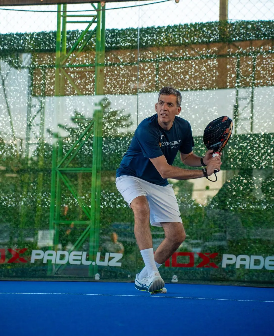 Victor Perez, international padel coach, preparing to play a shot on a blue padel court